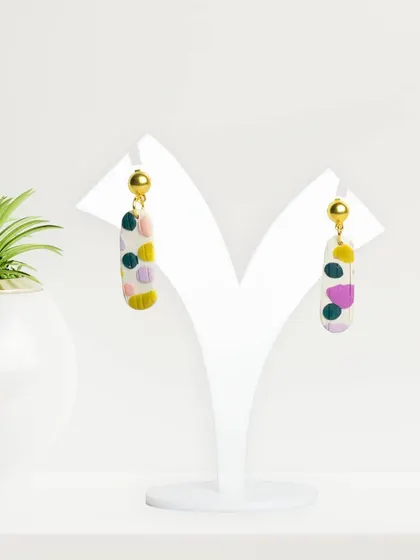 Colorful, patterned earrings displayed on a white stand. The high-key lighting ensures the colors are true-to-life and vibrant.