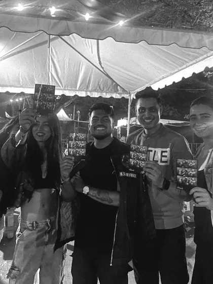 A group of friends at a night event, proudly displaying their photo strips. The fun doesn't stop when the sun goes down!