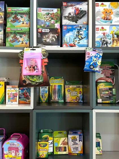 Our shelves are filled with more than just books. Here you can see a variety of toys, craft kits from brands like Crayola, and other fun items.
