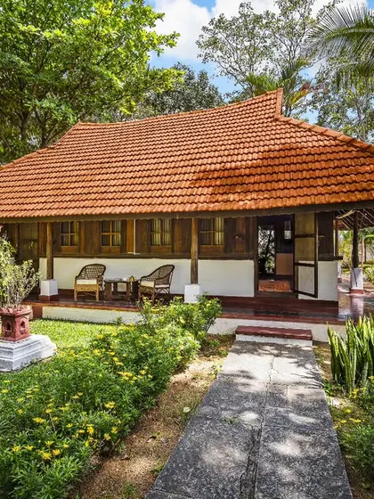 The inviting porch of the Ambara Mana cottage, a perfect spot to relax and enjoy the serene garden views. The traditional architecture promotes natural airflow and a connection to the outdoors.