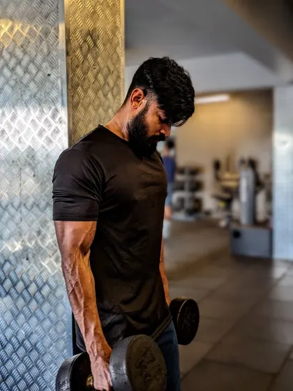 "Every workout is progress." A dumbbell curl, with a focus on the veiny, well-developed forearm.