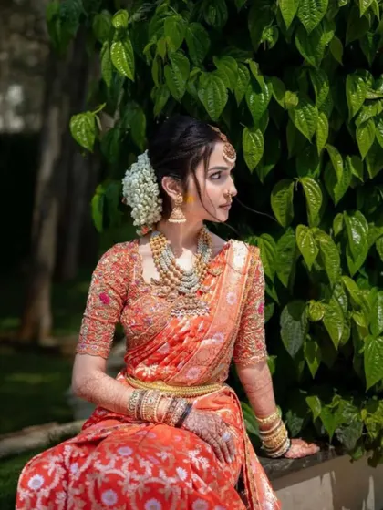 Another angle of this beautiful bride, showing the intricate details of her orange saree and the way the makeup enhances her features.