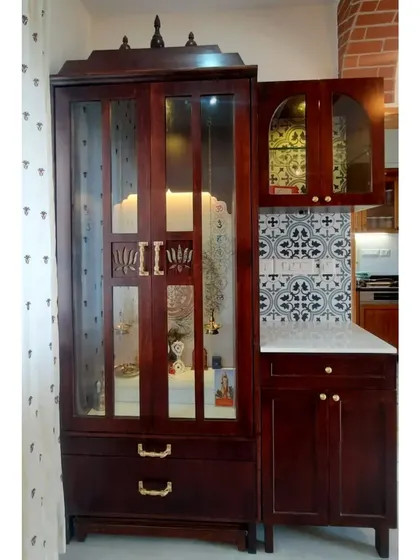 The pooja unit with its doors closed, showing the elegant design with glass panels and traditional finials on top. It stands as a beautiful piece of furniture in the home.