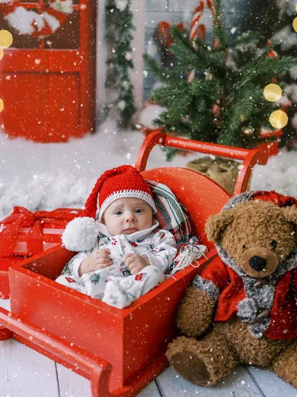 A newborn baby's first Christmas, nestled in a red sleigh. An incredibly precious and fleeting moment.