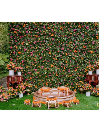 I believe a Haldi ceremony should radiate pure joy. Here, a lush wall of vibrant marigolds and roses creates a stunning backdrop, while traditional brass urlis and low seating invite guests into a space that feels both festive and intimate.
