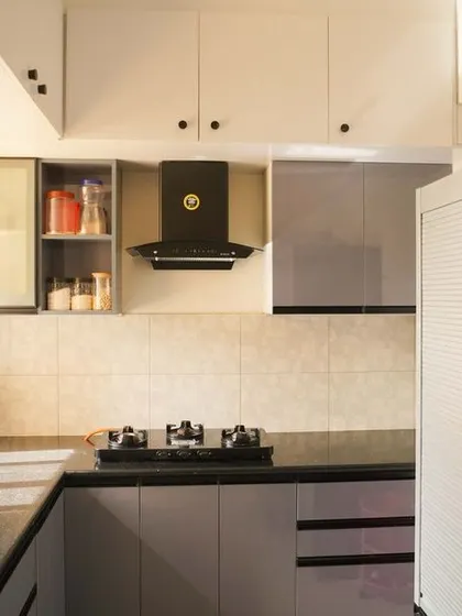 A wider perspective of the grey kitchen, showing the efficient use of space next to the refrigerator. The layout is designed to be both practical for daily cooking and visually cohesive.