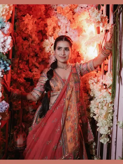 A solo portrait of the bride Kiran, radiant and happy against a backdrop of colorful flowers at her carnival-themed wedding event.