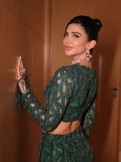 A chic and modern look in an emerald green fish-cut lehenga. The sleek bun and defined makeup create a sharp and sophisticated silhouette.
