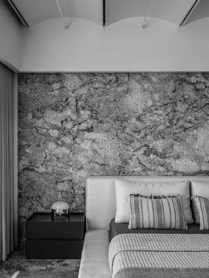 A detailed shot of the daughter's bedroom, focusing on the textural contrast between the soft bedding and the granite headboard.