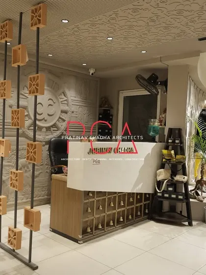 The reception desk at Jubinav Chadha Fashion Studio, with a custom partition made of terracotta blocks and a backdrop of carved wall panels.