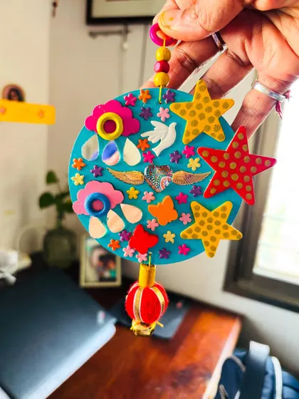 A close-up of the 'Our Angels' hanging. It's filled with tiny details like stars, clouds, doves, and angel wings, all representing the bright skies where our angels reside.
