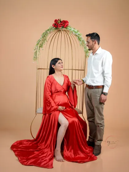 A romantic pose using our golden birdcage prop. The mom-to-be is seated while her partner stands beside her, creating a beautifully composed and elegant shot.