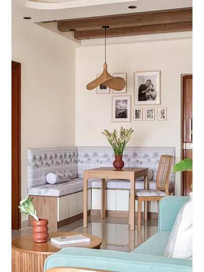 The dining nook in the same home uses an L-shaped bench with custom upholstery to maximize seating in a compact corner. A gallery wall of family photos adds a personal touch and conceals an electrical box.