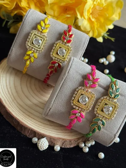 Elegant single rakhis with a leaf motif and a central stone. The vibrant enamel colors on the leaves make these designs stand out.