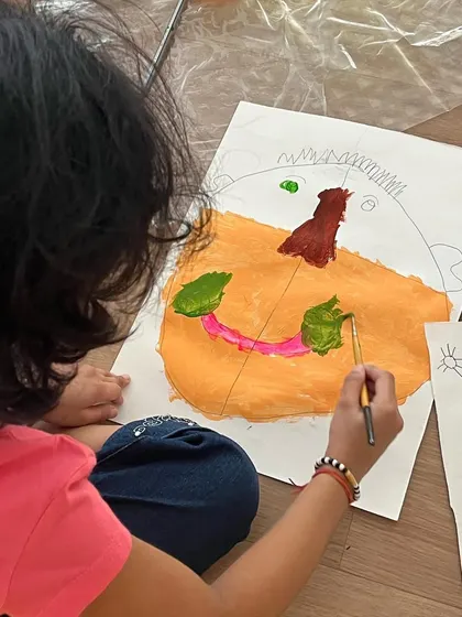 A young artist adding the final touches to her self-portrait. We guide them with basic proportions, but the style, color, and expression are entirely their own.