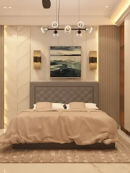 A luxurious master bedroom with a tufted grey headboard and a wardrobe with full-length mirrored panels. The use of gold-finish handles and warm lighting creates a sophisticated and glamorous feel.