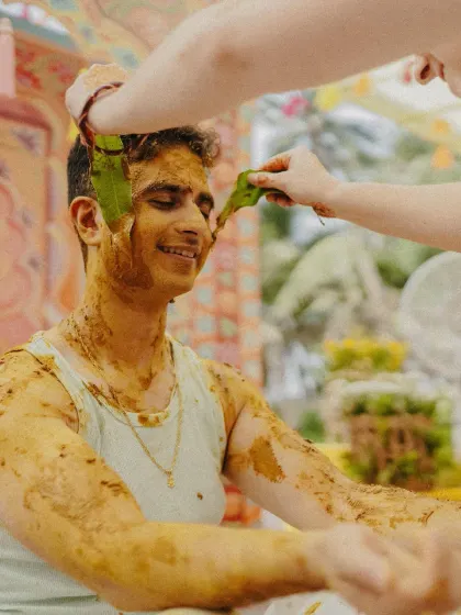 The groom being blessed with mango leaves during the Haldi ritual, a beautiful tradition we incorporate into our planning.