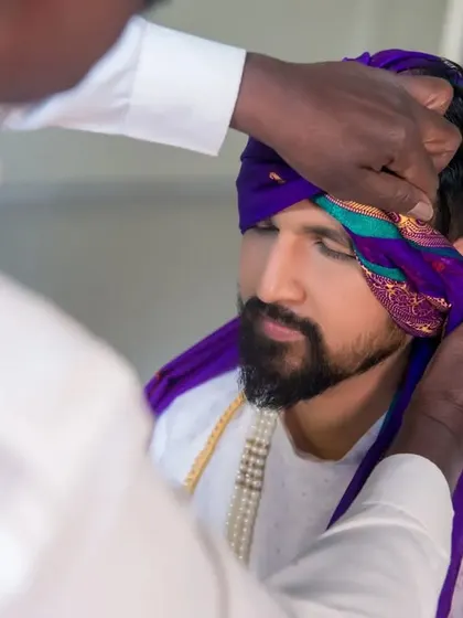 Another angle of the turban-tying process, showing the care and tradition involved in the groom's preparation.