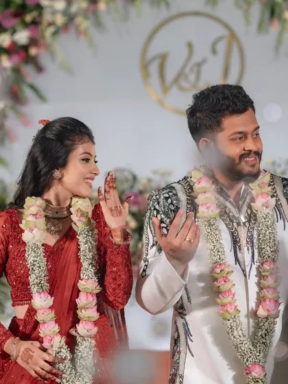 A candid shot of the happy couple during their reception, framed by lotus-themed floral garlands. The joy on their faces is a reflection of a perfectly executed event.