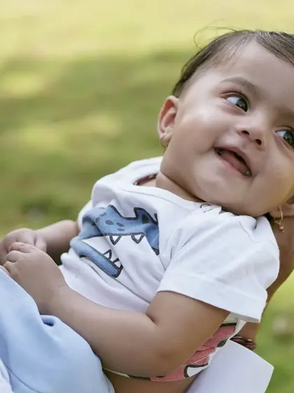 A father holds his baby, who is looking back at him with a beautiful, trusting smile. A heartwarming candid moment.
