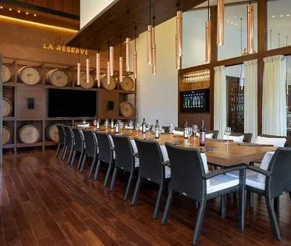Another view of the 'Cave de la Reserve', showcasing the elegant long table and custom lighting. This room is designed to provide an immersive and sophisticated environment for enjoying our finest wines.