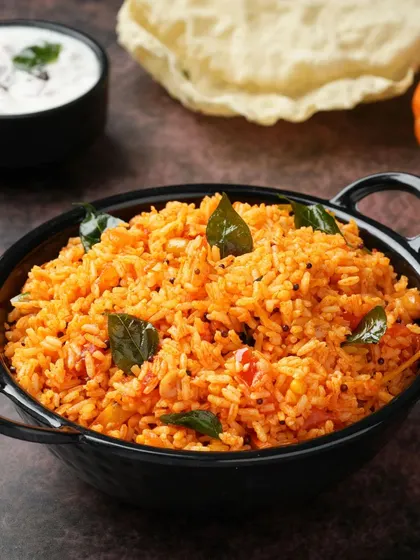 The rich color of this Tomato Rice is its main appeal. We used dark, moody lighting to make the colors pop and highlight the fresh curry leaves, making a simple dish look exceptionally flavorful.