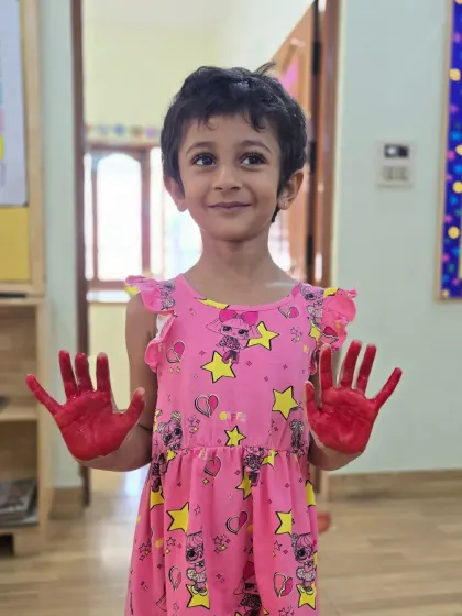A happy camper proudly shows off her red-painted hands, ready to make her mark. This sensory painting activity is a fantastic way for kids to explore colors and textures.