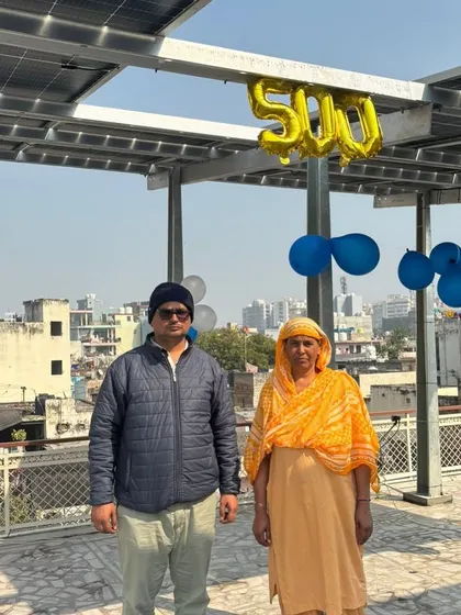 A couple stands on their rooftop, celebrating being the 500th customer in Delhi NCR with balloons and their new solar system.