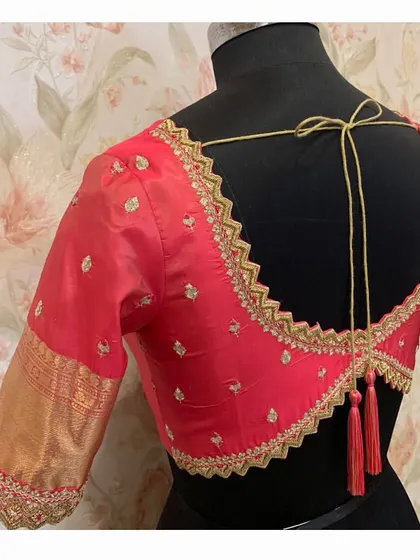 A classic red blouse with a cutwork back design, edged with intricate gold embroidery and finished with elegant tassels.