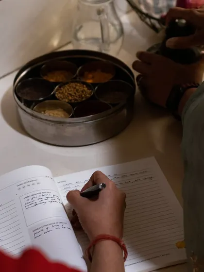 The best recipes are born from observation and scribbled notes. Here, a family recipe is being documented right in the heart of the kitchen, next to the masala dabba. Our journals are designed to be used, to gather stains and stories, and to become a living document of a family's culinary history.