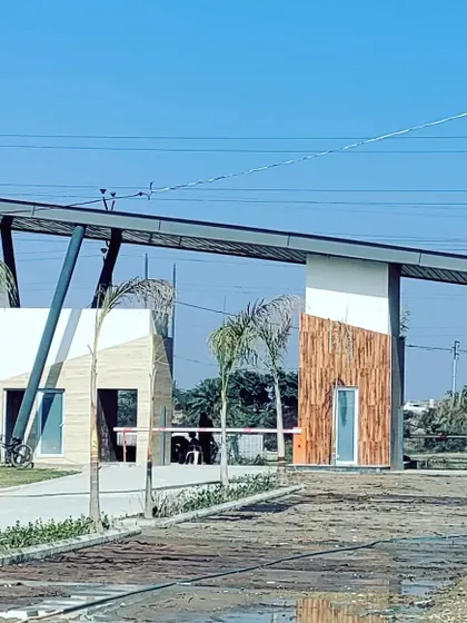 The main gate of the Kanpur row housing project, post-construction. This image shows the successful translation of our design render into a physical structure, featuring a mix of wood-textured panels and angled steel supports.