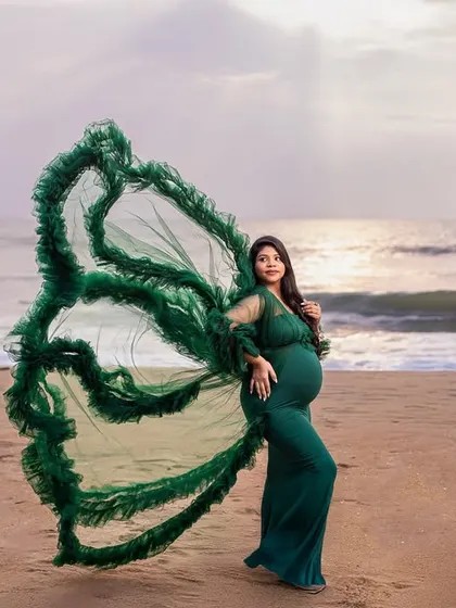 An emerald green gown with butterfly wings creates a stunning, ethereal look against the ocean. This is a perfect example of how we combine unique props with natural beauty for an unforgettable beach maternity shoot.