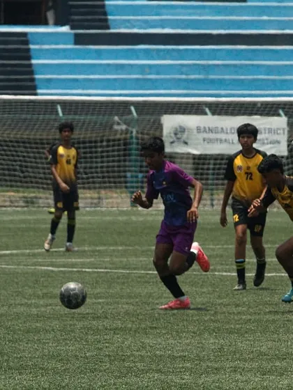A player dribbles past a defender in the YPL finals at Bangalore Football Stadium. These high-stakes games are crucial for player development.