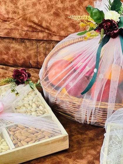 A beautifully composed shot of a dry fruit box and a fruit basket. The soft pink net on the box contrasts nicely with the white net on the basket.