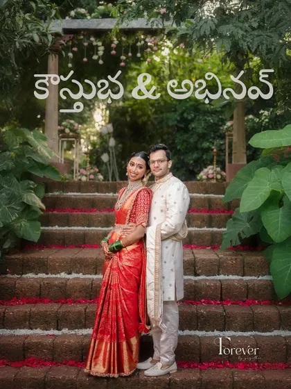 A wedding poster-style shot of the couple, capturing their complete traditional outfits and the beautiful, lush backdrop of their wedding venue.