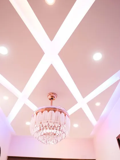A stunning false ceiling design with a geometric pattern and a beautiful crystal chandelier, adding a touch of glamour and sophistication to the room.