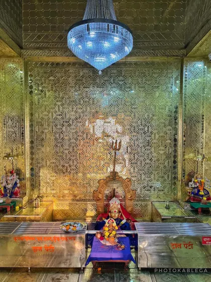The inner sanctum of the temple, with the deity placed against a glittering golden wall.