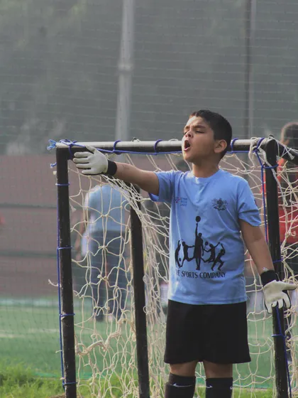 A young goalkeeper directs his defense during a crucial moment in the game. We empower our players to be leaders on the field, developing their communication and strategic thinking from an early age.