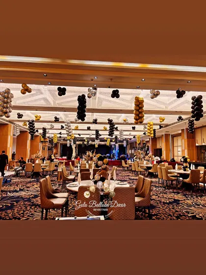 The full banquet hall setup for a glam 18th birthday, with black, gold, and silver balloon bunches hanging from the ceiling.