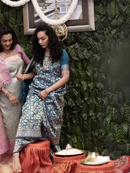 A mother and daughter share a moment in front of a unique backdrop made entirely of fresh coffee leaves from their family's estate in Coorg. This is the ultimate in personalized and locally-sourced decor.