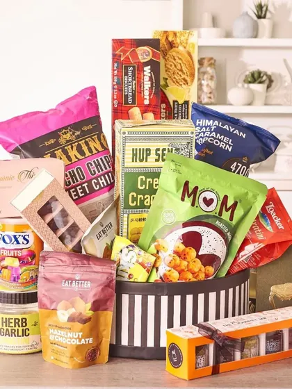 Perfect for sharing, this hamper is filled to the brim with a variety of snacks, from savory crackers and popcorn to sweet brownies and fruit candies, all presented in a stylish striped hatbox.