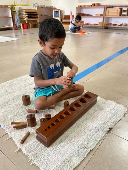 The Cylinder Blocks are a foundational sensorial material. By fitting each cylinder into its correct socket, the child refines their pincer grip for writing and develops their ability to visually discriminate between different dimensions.
