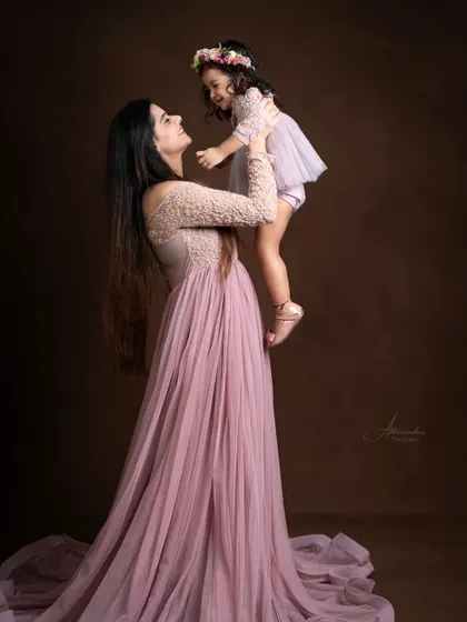 A mother lovingly lifts her daughter, creating a beautiful, dynamic portrait.