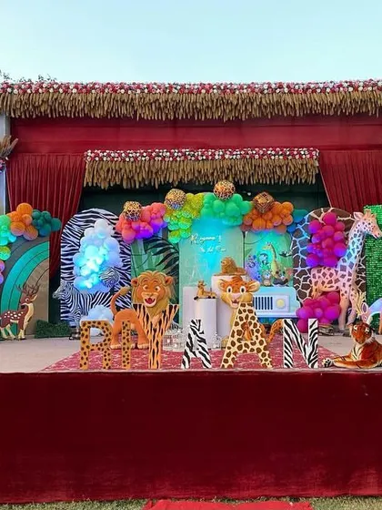 I can transform any large outdoor space, like this farmhouse lawn, into a vibrant jungle. This setup features a massive stage with life-sized animal props like elephants and giraffes, themed backdrops, and colorful balloon arrangements to create an immersive safari experience for a child's birthday.