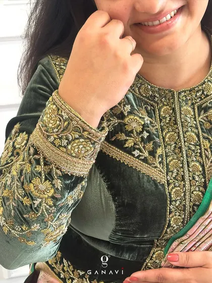 A close-up of a client wearing a bespoke royal green velvet blouse. The piece is detailed with intricate gold zardozi work, telling a story of timeless grace and heritage fashion.
