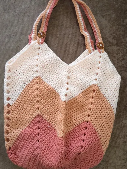 This is the Chevron Tulip Bag in a different colorway, using shades of cream, beige, and pink. The button details on the straps add a lovely finishing touch to this handmade tote.