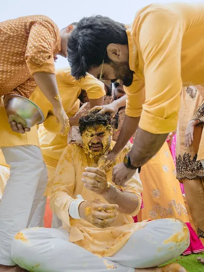 A candid shot of the groom getting covered in haldi by his friends. His expression is a perfect mix of surprise and fun.