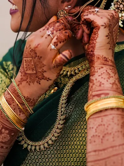 A candid shot of a woman adjusting her jewelry, with her beautiful henna on display. This is a great example of henna for a party or family function.