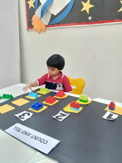 This young learner is deeply engaged in our block counting exercise. By physically handling the blocks, he develops a tangible understanding of numbers and patterns, which is a core part of our creative math enrichment.