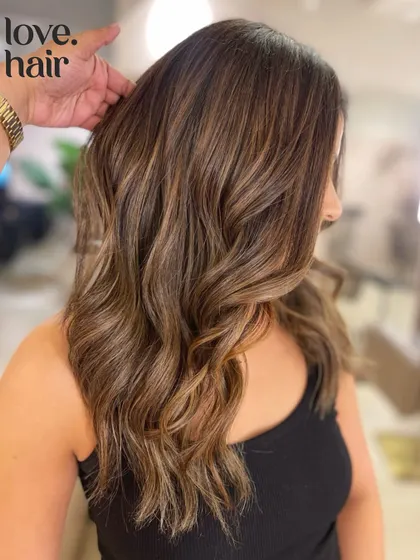 A side view of this sugar and honey balayage, highlighting the face-framing pieces and the seamless color melt.